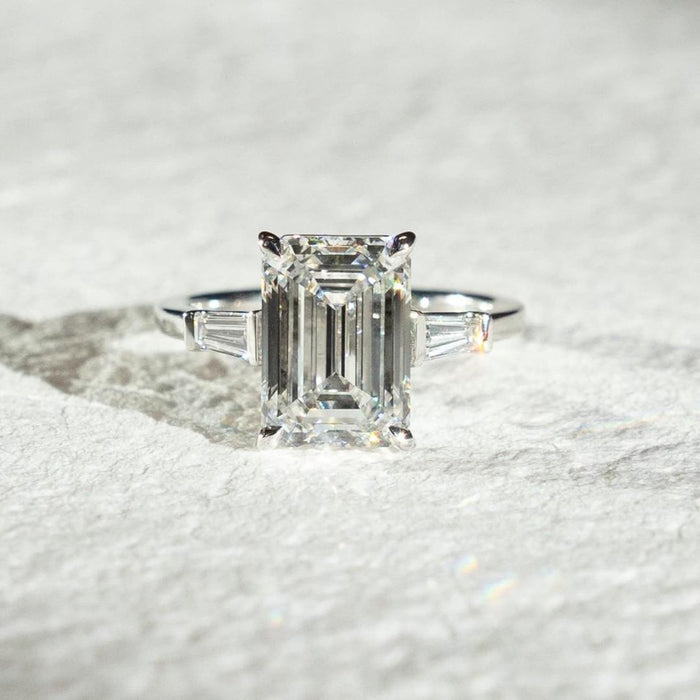 Tapered baguette side stones angled toward the emerald cut center diamond