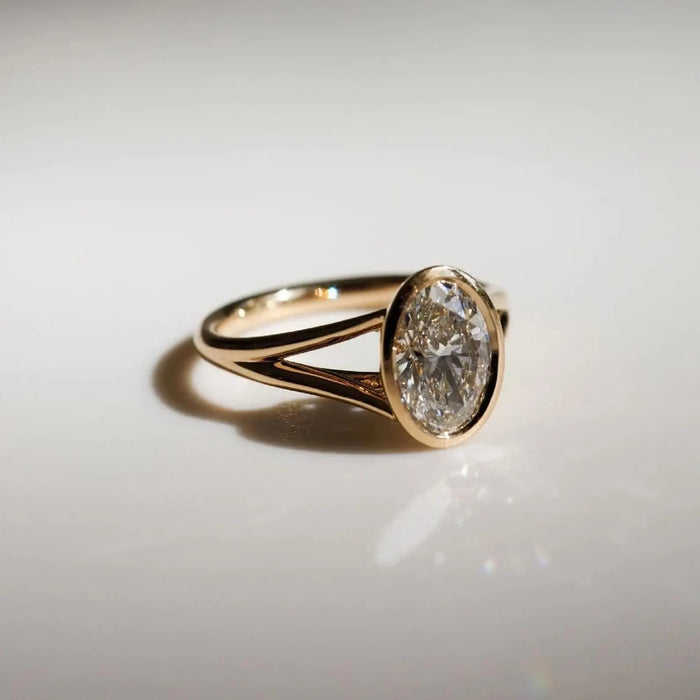 Oval cut lab grown diamond in a full bezel between two split shank strands