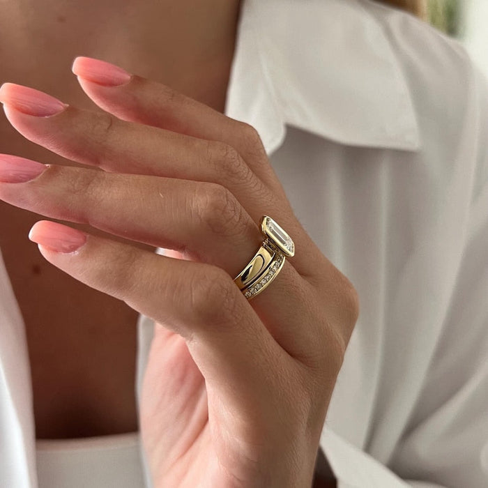 Side view of emerald cut moissanite bezel ring with wide polished shank and pave band