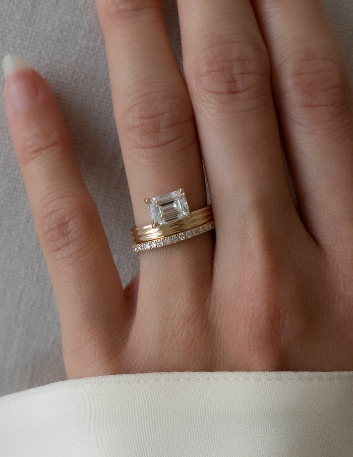Emerald cut moissanite bridal set with triple-ridge shank and straight pave band in yellow gold
