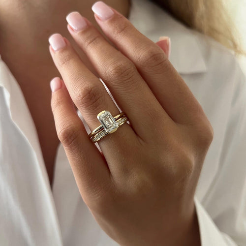 Emerald cut moissanite half bezel bridal set in yellow gold worn on the hand