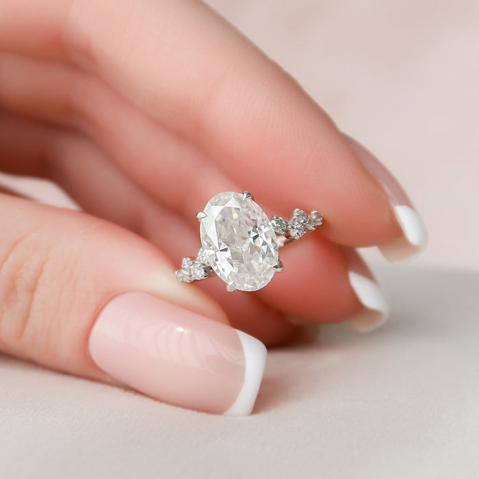 Oval cut moissanite hidden halo cluster engagement ring in white gold held in hand