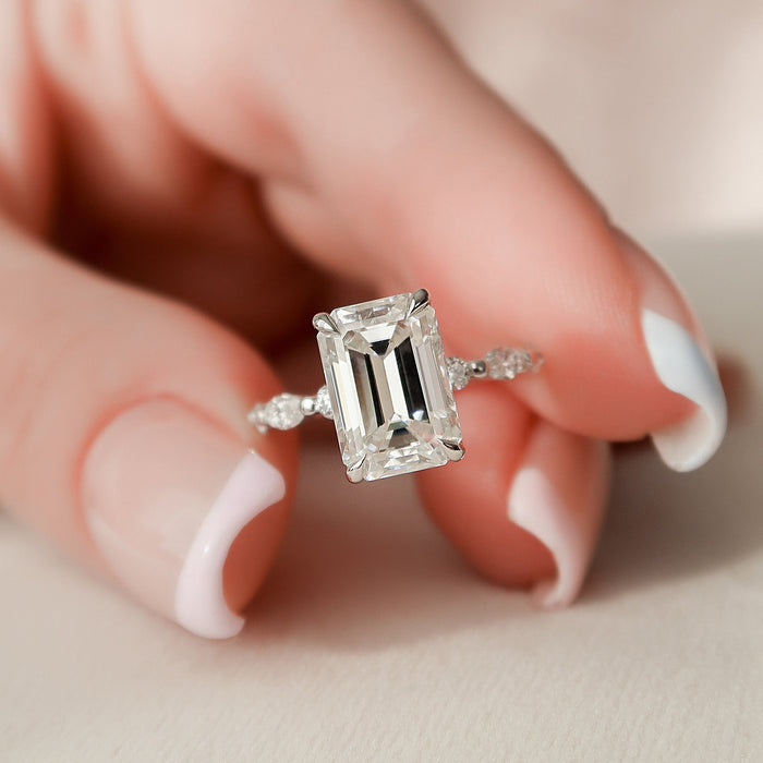 Emerald cut moissanite hidden halo engagement ring in white gold held in hand