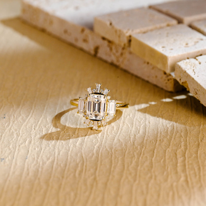Emerald cut moissanite Art Deco sunburst engagement ring with an emerald cut on each side and a fan of tapered baguettes at the top and bottom in yellow gold