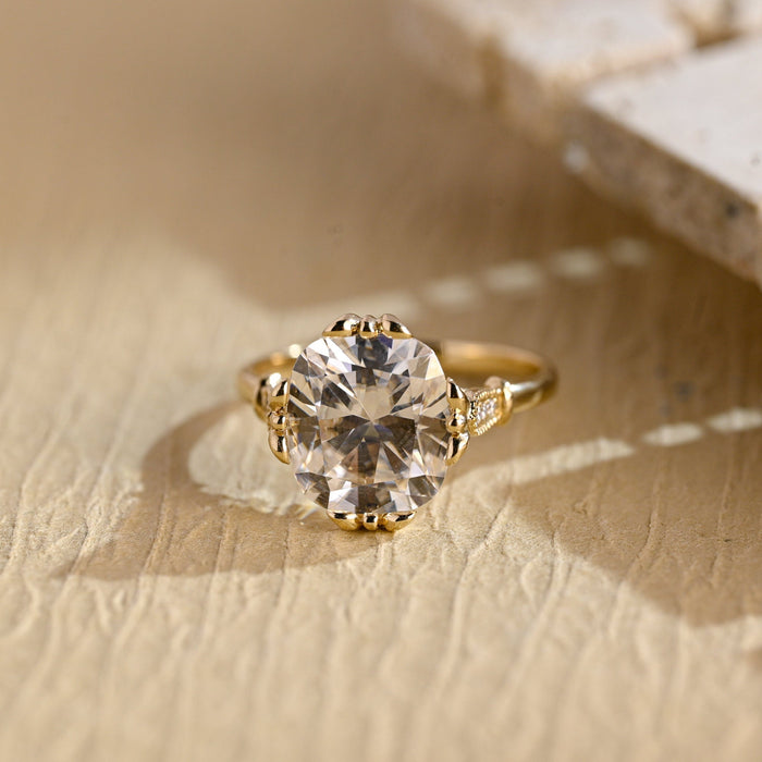 Elongated cushion moissanite vintage engagement ring with four ornate floral claws and milgrain shoulders set with small round stones on a yellow gold band