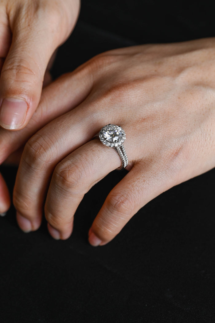 Round moissanite halo engagement ring in six claws with a fine split shank of two slender pave set strands in white gold, view 2