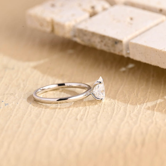 Upright pear moissanite solitaire engagement ring set point up in four slim claws on a thin polished white gold band, view 2
