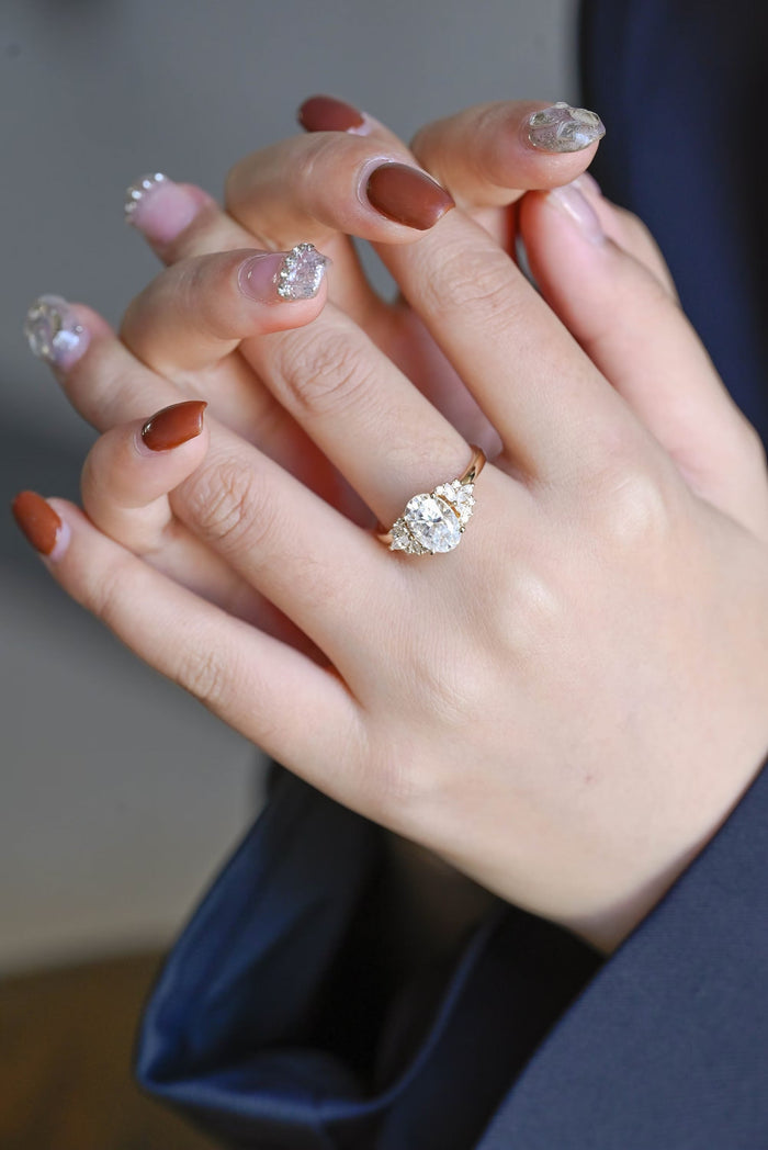 Oval moissanite engagement ring with a fan of marquise and small round stones on each side of the oval on a slim plain yellow gold band, view 2
