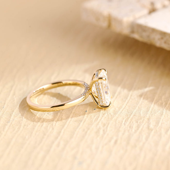 Elongated radiant cut moissanite hidden halo engagement ring in four claws on a polished yellow gold band with small flush set shoulder stones, view 2