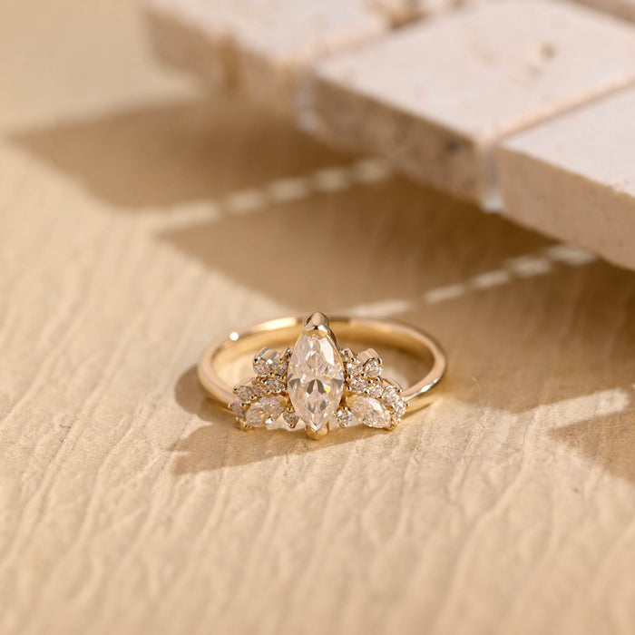 Marquise cut moissanite wing cluster engagement ring with round and marquise accent stones on a slim yellow gold band