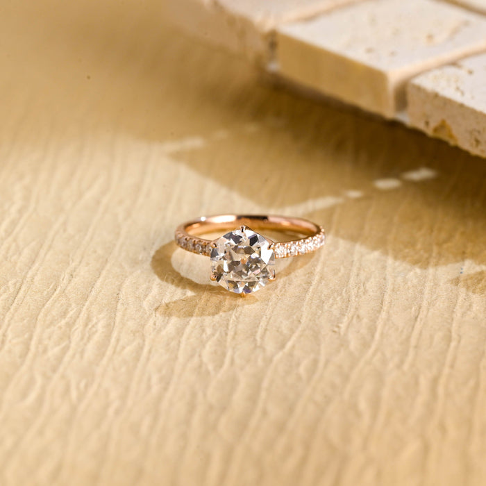 Round moissanite solitaire engagement ring in a six claw tulip setting with a pave set rose gold band