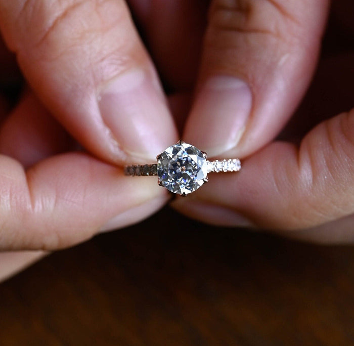 Round moissanite solitaire engagement ring in a six claw tulip setting with a pave set rose gold band, view 2