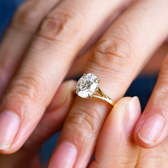 Oval moissanite solitaire engagement ring in four slim claws on a polished yellow gold split shank band, view 2