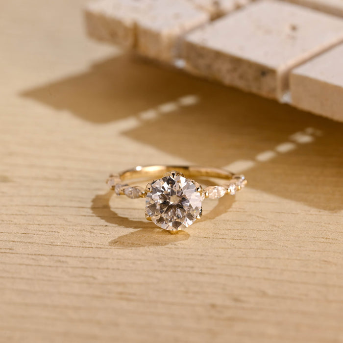 Round moissanite solitaire engagement ring in six claws with a slim yellow gold band set with alternating marquise and small round stones