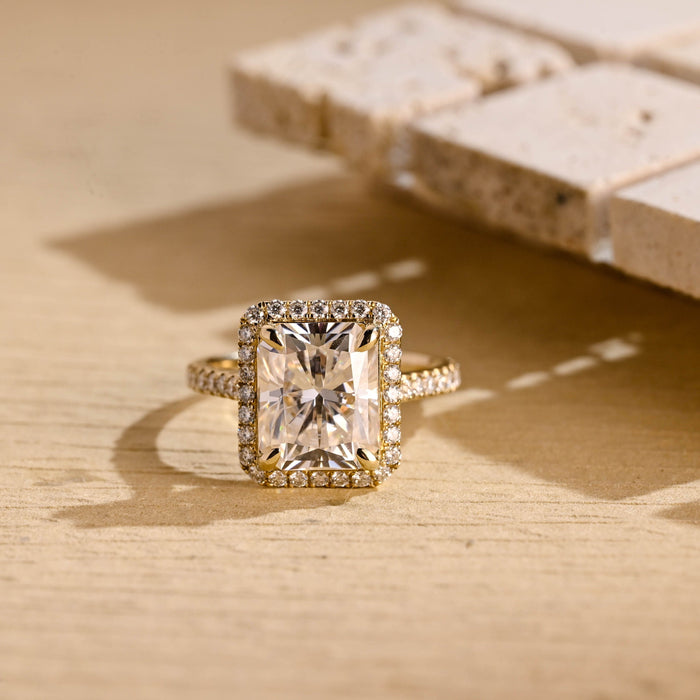 Radiant cut moissanite halo engagement ring in four claws with a pave set yellow gold band