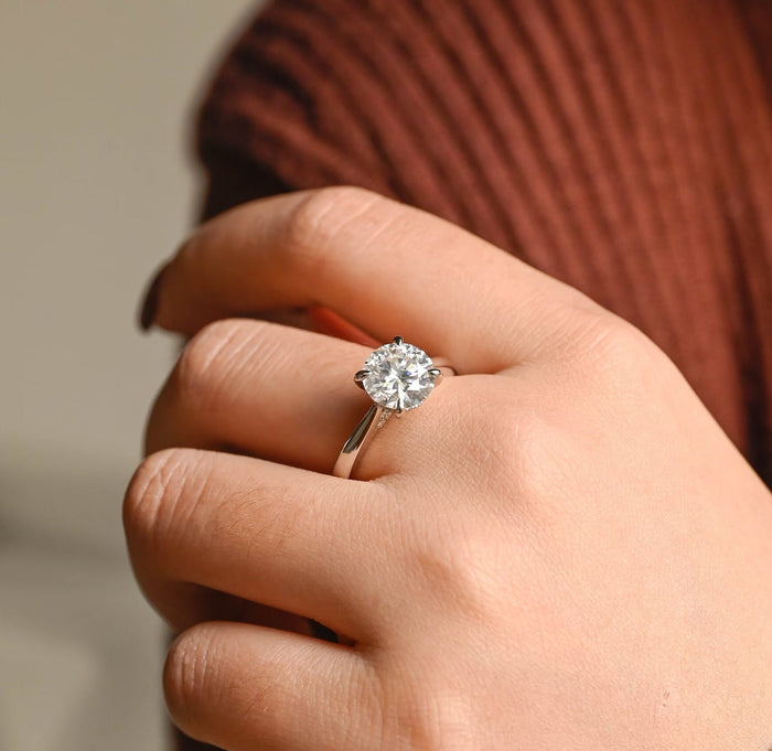 Round moissanite hidden halo engagement ring in four claws on a smooth polished white gold band that tapers up to the stone, view 2