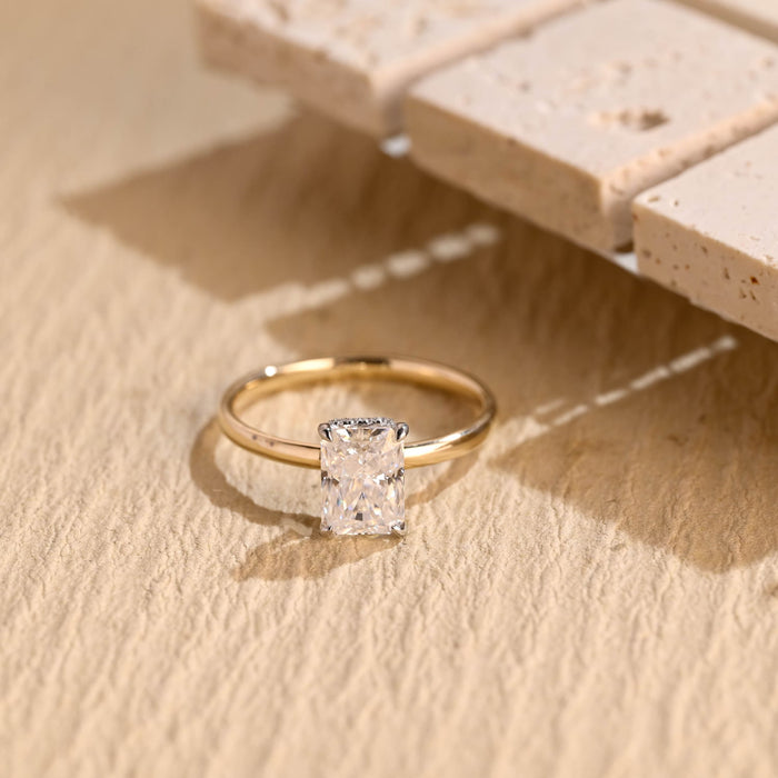 Radiant cut moissanite hidden halo engagement ring with white claws on a thin polished yellow gold band