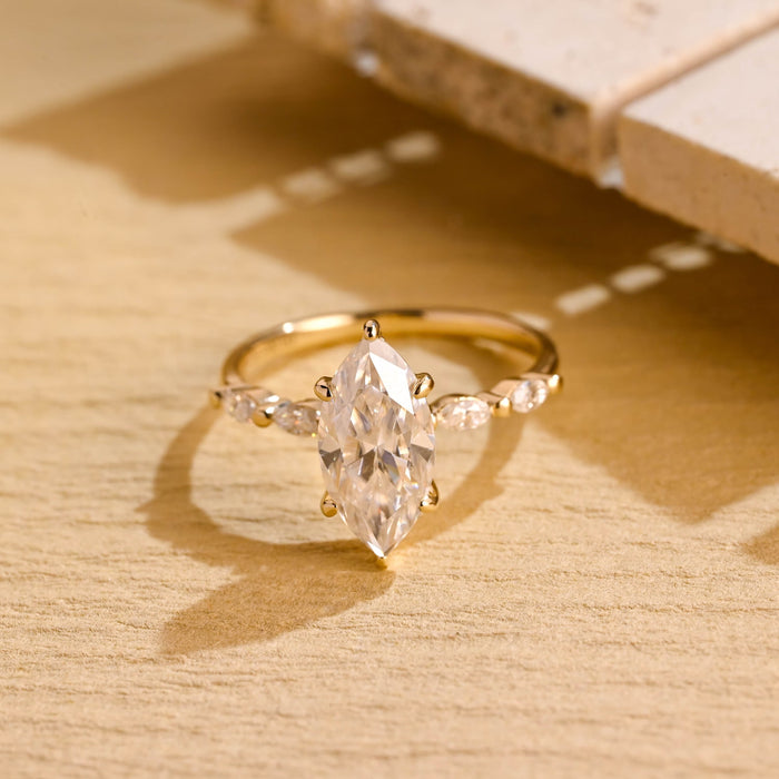 Marquise moissanite engagement ring held by six claws with small marquise accent stones set along a slim polished yellow gold band