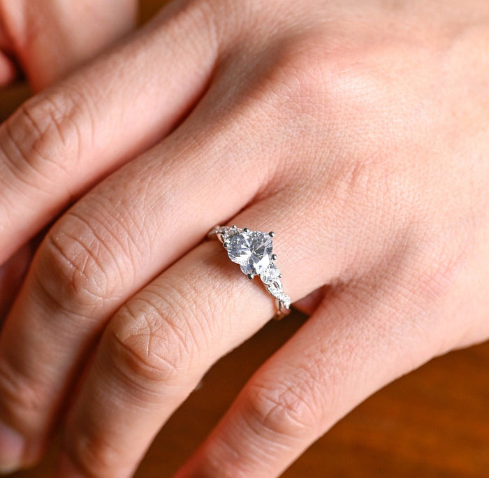 Heart cut moissanite three stone engagement ring with round side stones on a twisted pave set white gold band, view 2