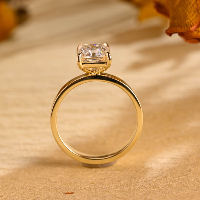 Radiant cut moissanite solitaire engagement ring with four claws on a wide flat polished yellow gold band, view 2