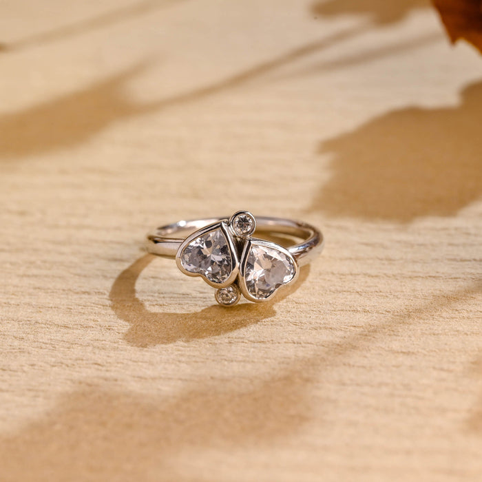 Toi et moi two stone heart cut moissanite bezel engagement ring with two round accent stones on a white gold band