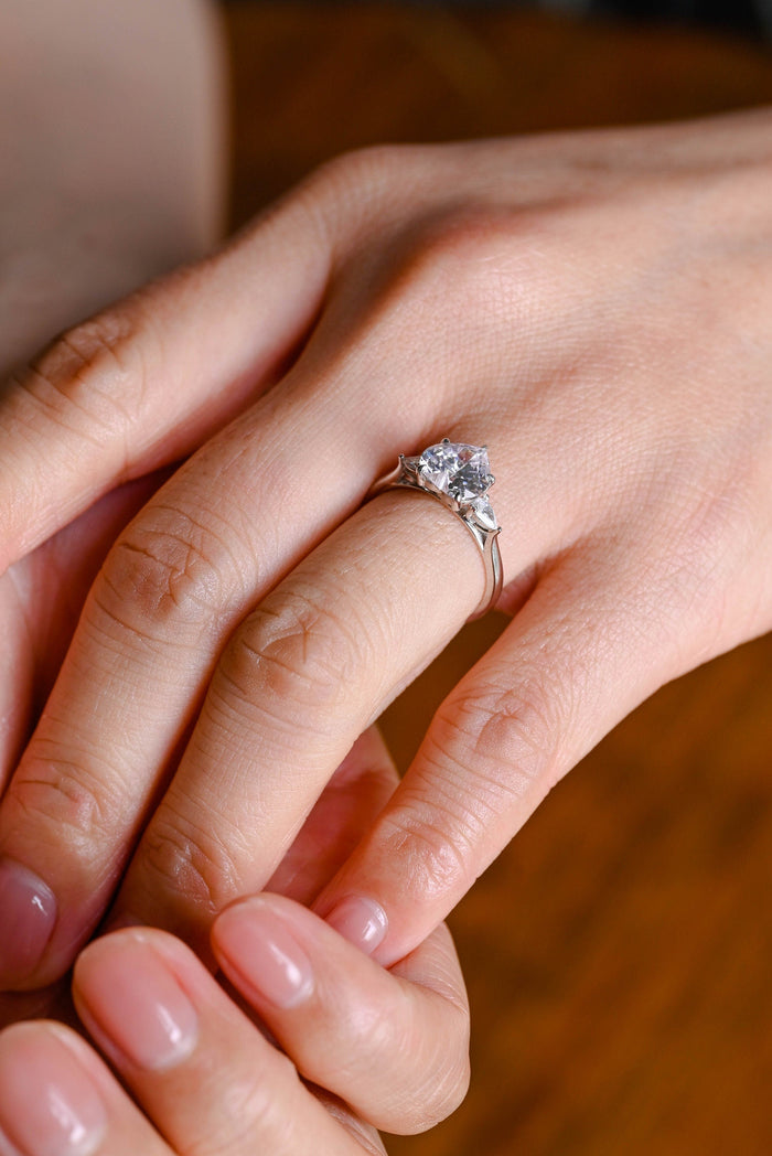 Heart cut moissanite three stone engagement ring with pear cut side stones on a polished white gold band, view 2