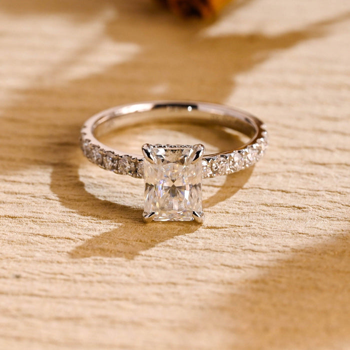 Radiant cut moissanite hidden halo engagement ring in four claws with a graduated pave set white gold band