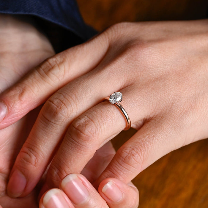 Oval moissanite solitaire engagement ring held by six slim claws on a slim polished rose gold band, view 2