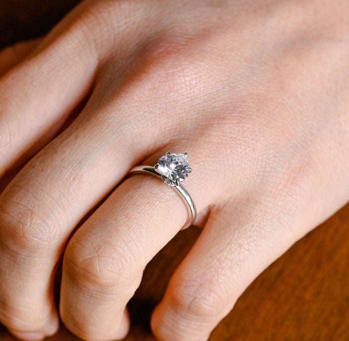 Heart cut moissanite solitaire engagement ring with hidden halo on a plain polished white gold band, view 2