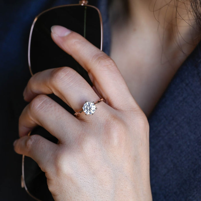 Round moissanite solitaire engagement ring in six ball tipped claws on a slim twisted rope band in rose gold, view 2