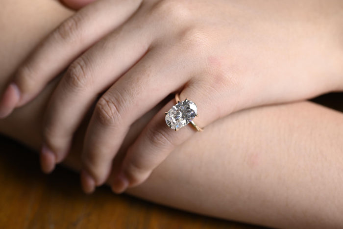 Oval moissanite solitaire engagement ring in four slim claws on a plain polished round yellow gold band, view 2