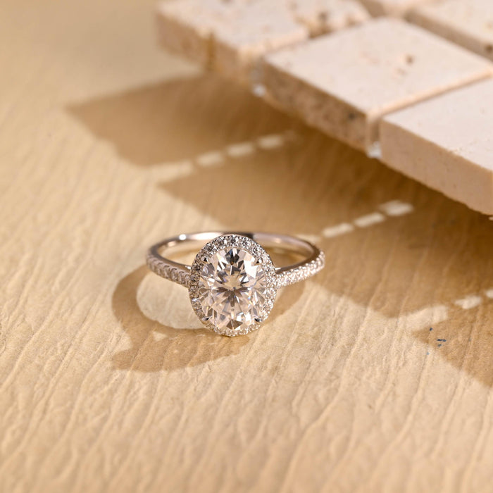 Oval moissanite classic halo engagement ring with a single pave halo and a slim pave set white gold band