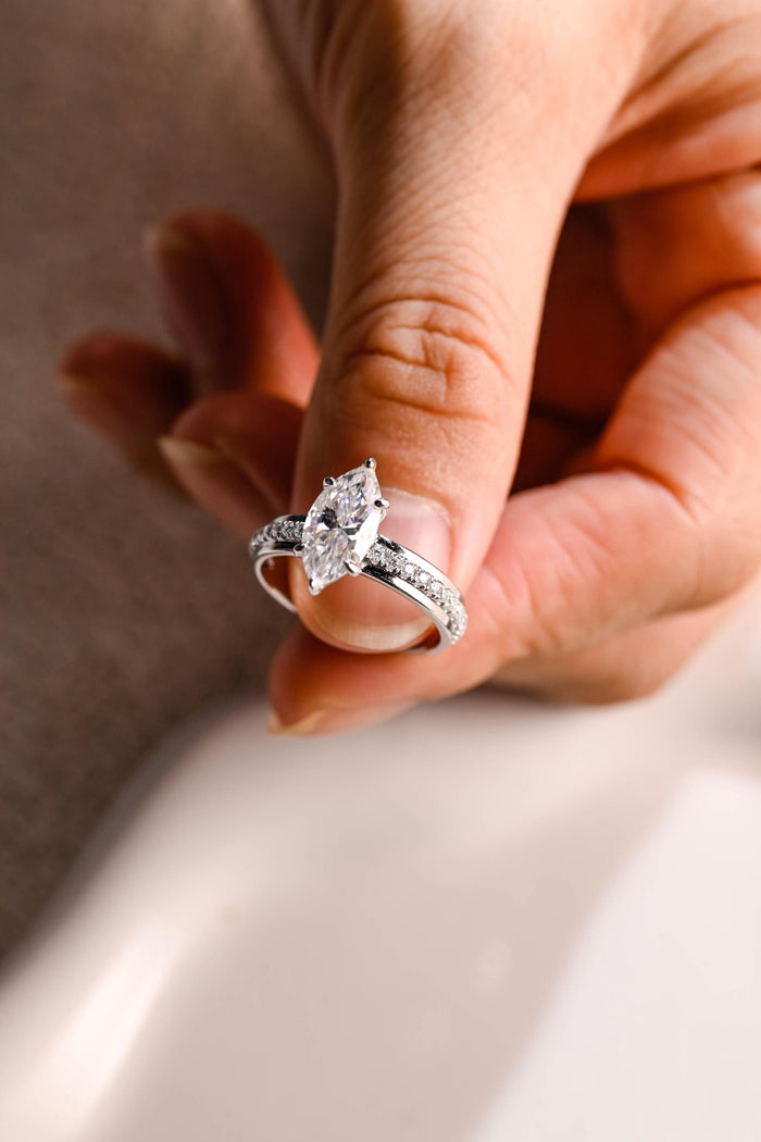 Marquise cut moissanite six claw solitaire ring on a white gold band with pave stones set into the sides, view 2