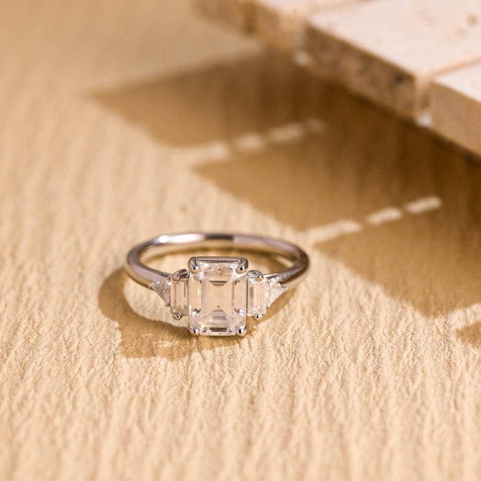 Emerald cut moissanite five stone engagement ring with baguette and trillion side stones on a slim white gold band