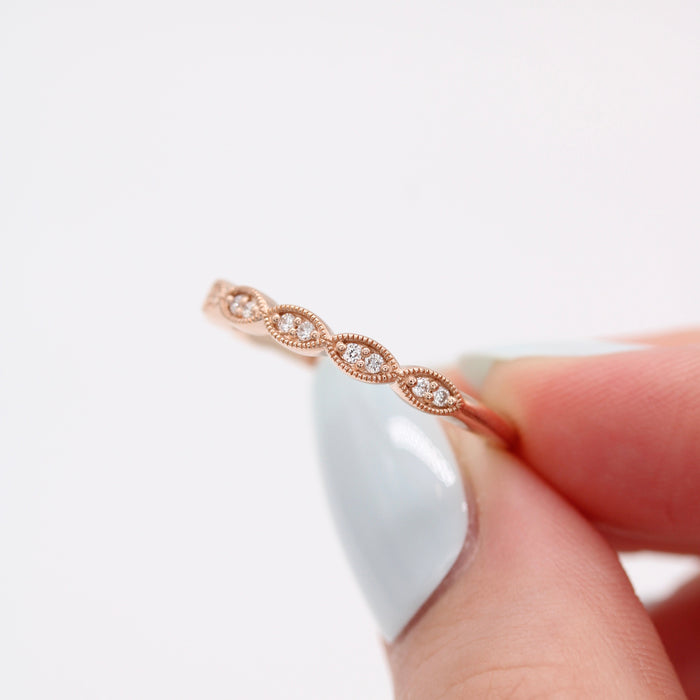 Round moissanite milgrain vintage wedding band in rose gold, held in a hand