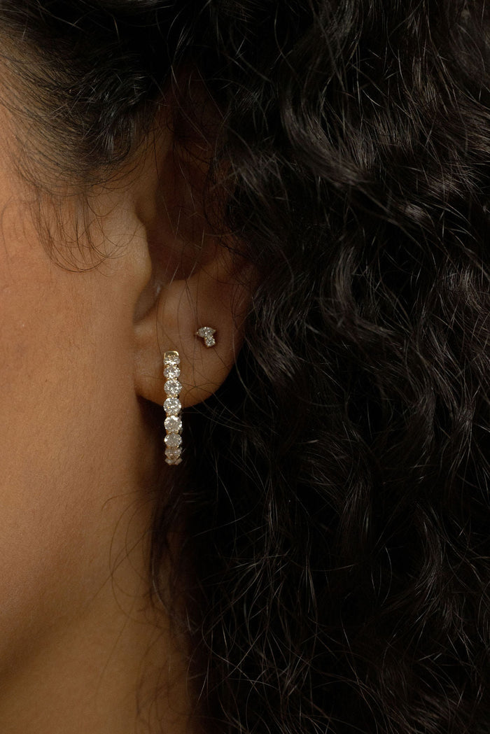 Ear lobe wearing a marquise and round lab grown diamond cluster stud earring beside a large lab grown diamond hoop