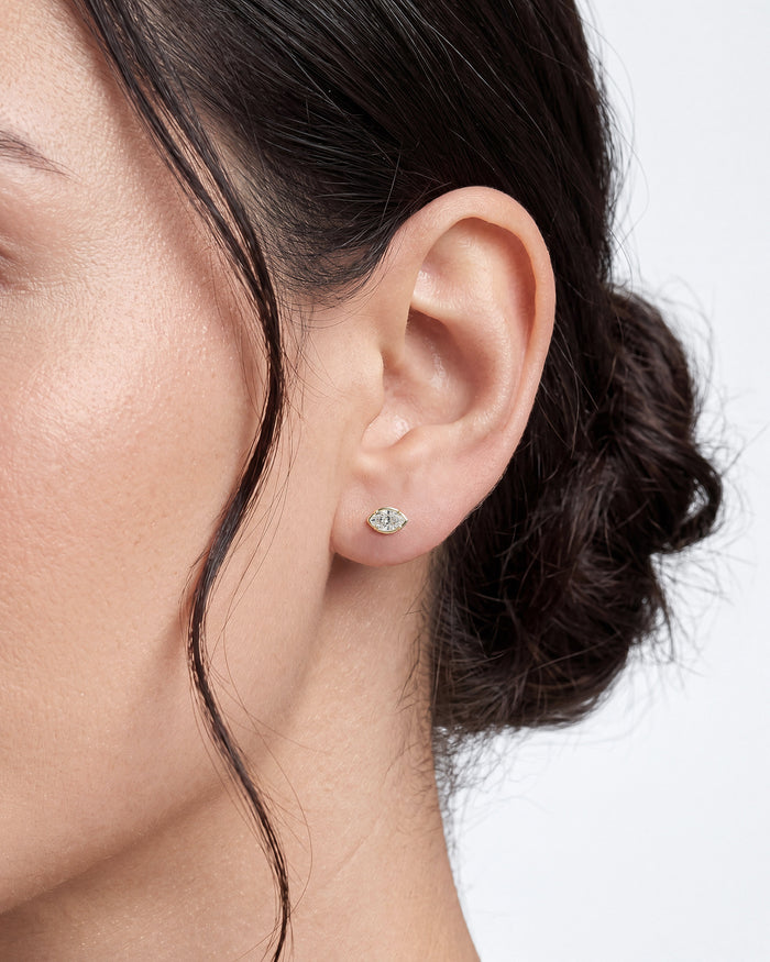 Model wearing marquise bezel set solitaire lab grown diamond stud earrings, close up on the ear