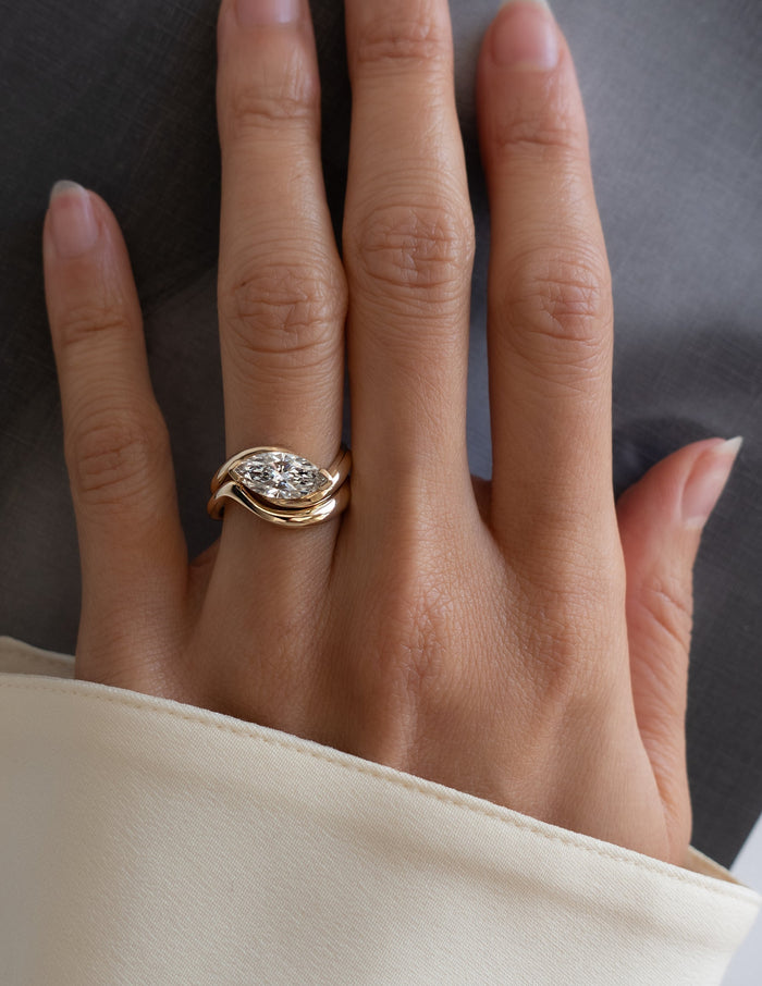 East-west marquise lab grown diamond solitaire and plain gold wave band shown on the full hand