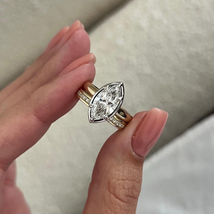 Marquise moissanite bezel solitaire and flat stone row band held in the fingers