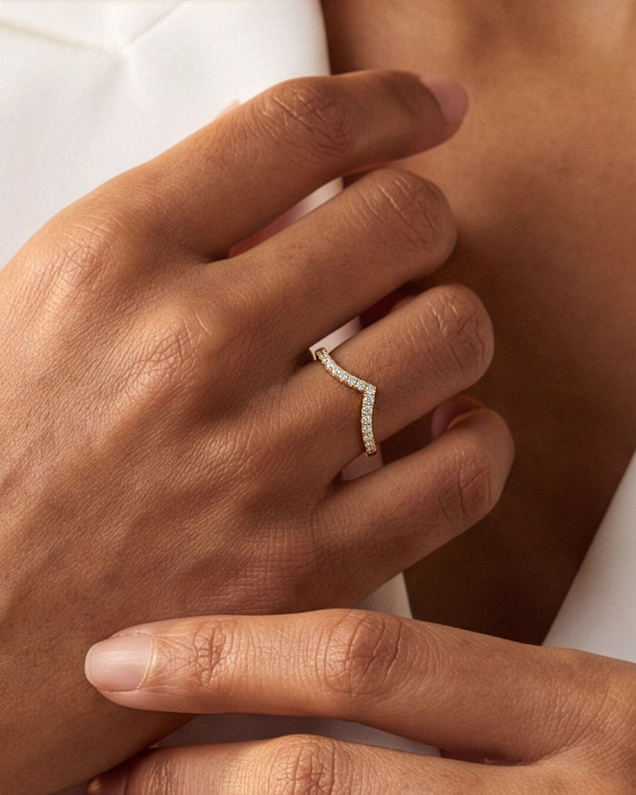 Curved moissanite wedding band worn on the ring finger
