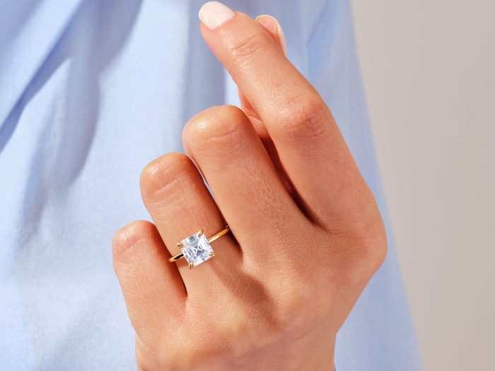 Asscher lab grown diamond statement solitaire in yellow gold on a raised hand against a blue shirt