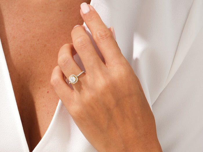Cushion moissanite pave halo ring worn on the ring finger, hand resting on the collar