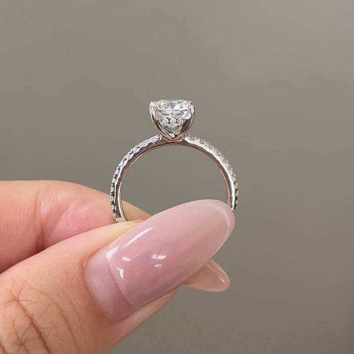 Cushion cut moissanite hidden halo engagement ring on a pave set white gold band, view 2
