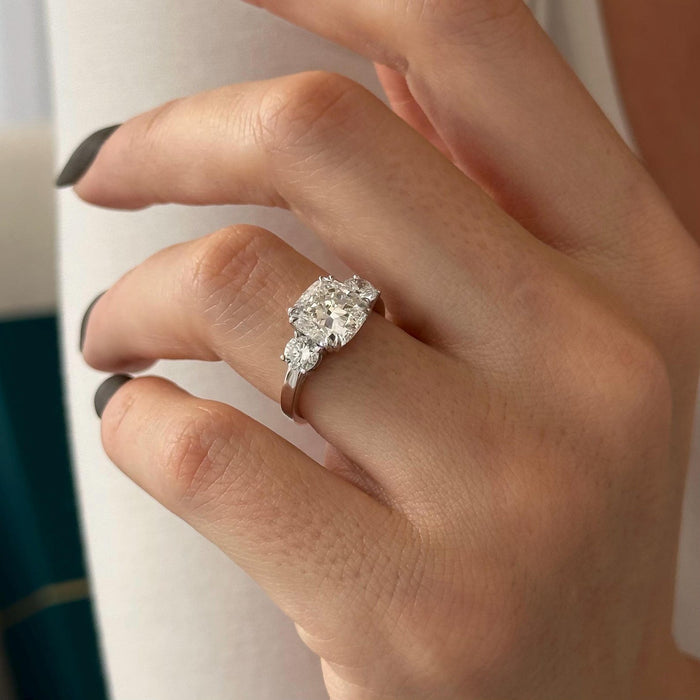Cushion cut moissanite three stone engagement ring with round side stones in white gold, view 2