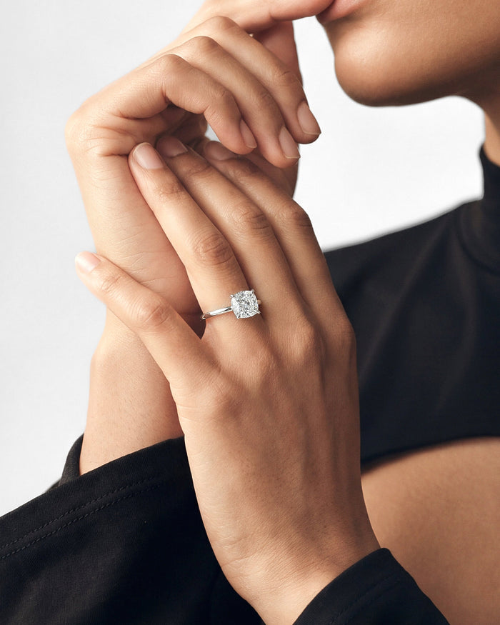 Large cushion cut lab grown diamond solitaire in white gold worn on clasped hands
