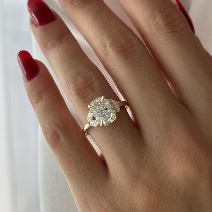 Elongated cushion moissanite three stone engagement ring with marquise side stones in yellow gold