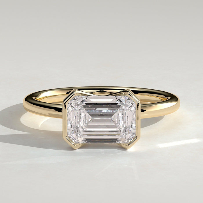 East west emerald cut moissanite corner panel bezel engagement ring in yellow gold