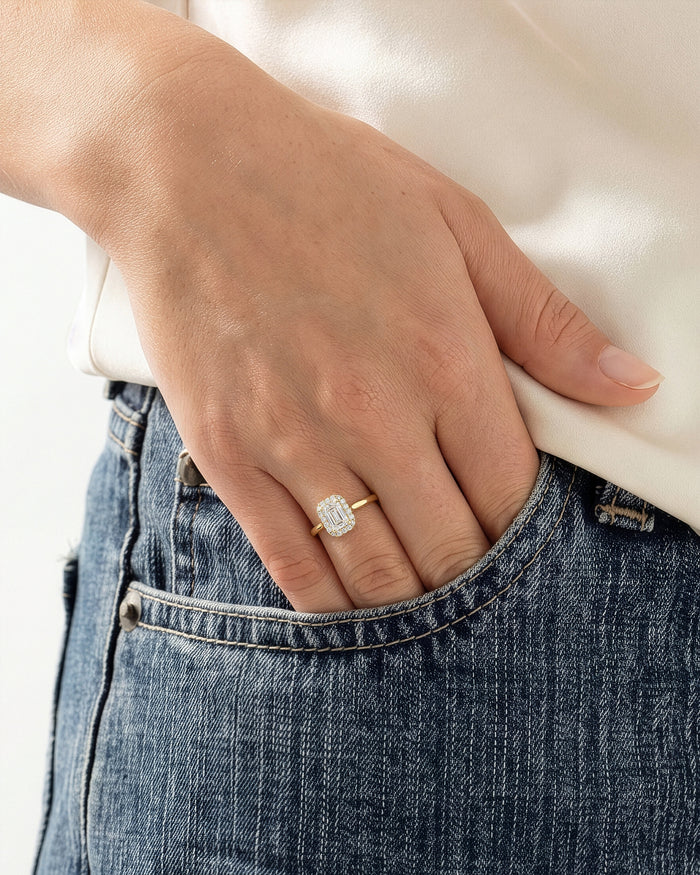 Emerald lab grown diamond halo ring in yellow gold worn on a hand tucked into a denim pocket