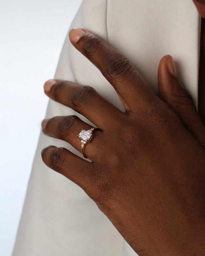 Emerald cut lab grown diamond marquise accent ring in rose gold worn on a hand against a cream coat