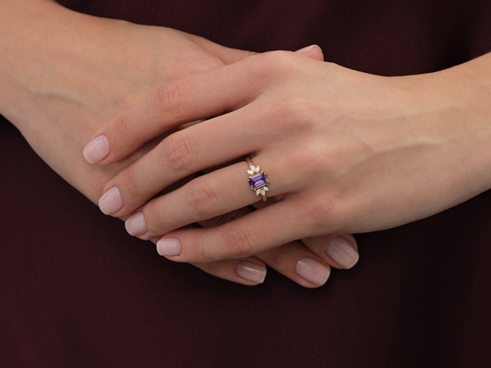 Emerald cut marquise leaf ring setting in yellow gold worn on folded hands, purple display stone